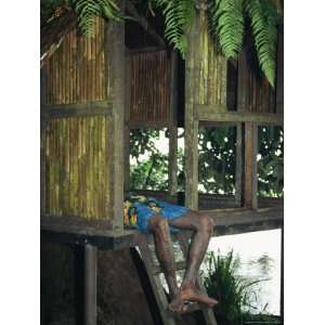  A Man Resting in the Doorway of an Elevated Hut Premium 